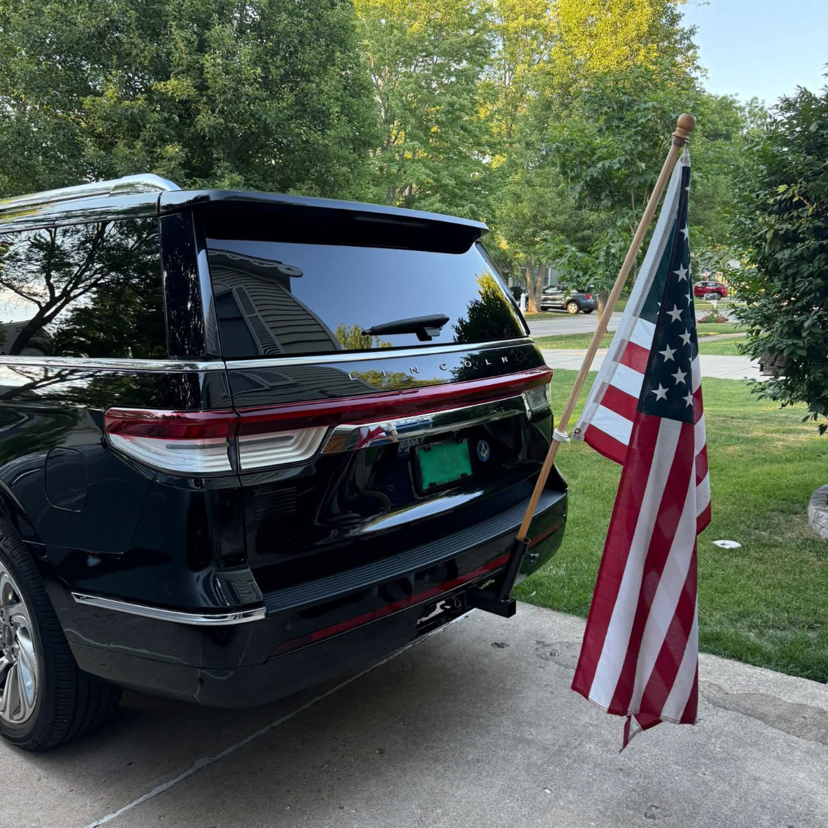 Black SUV in suburban driveway with American flag