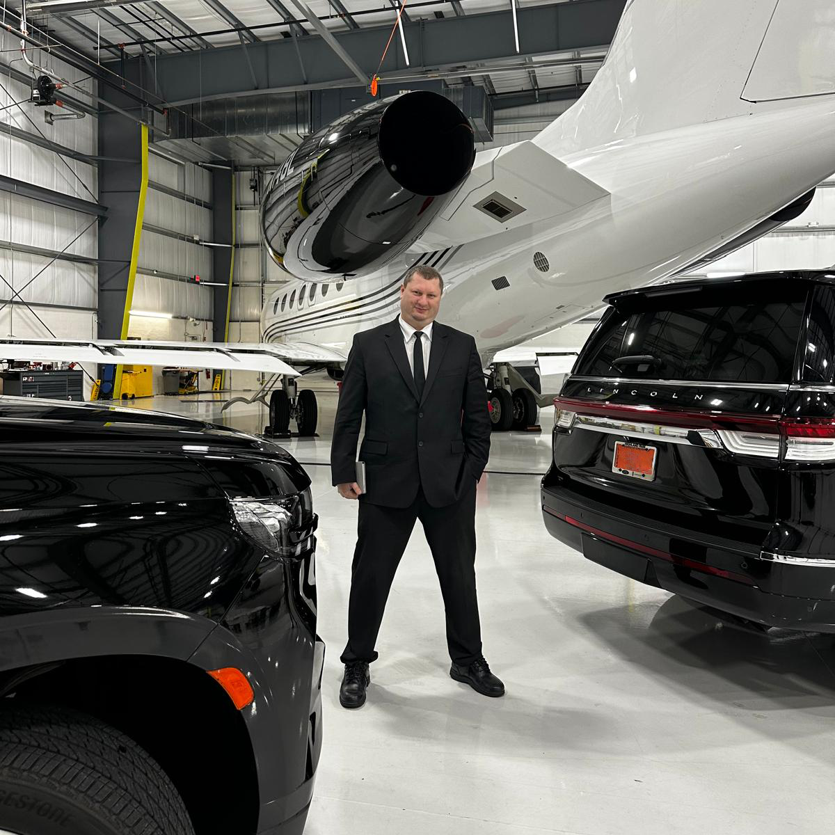Senior executive chauffeur next to a private jet in hangar